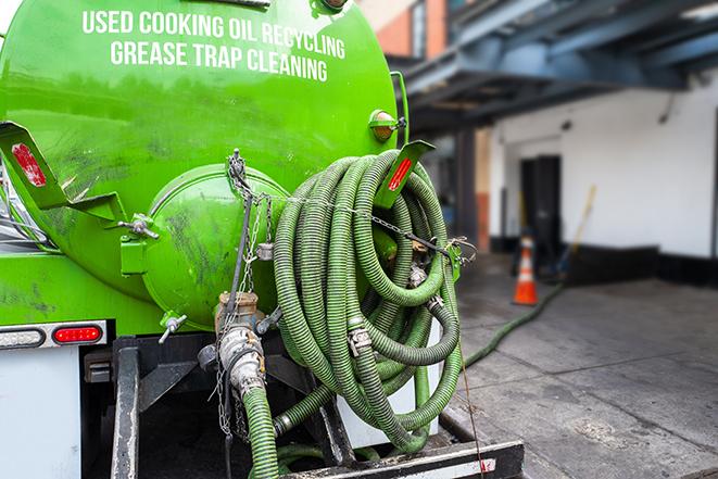 a technician pumping a grease trap in a commercial building in Clay